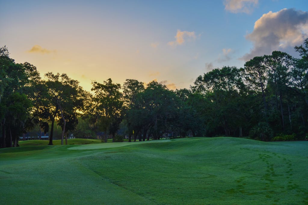 A serene golf course landscape at sunset in Savannah, GA, showcasing vibrant greens and a colorful sky.